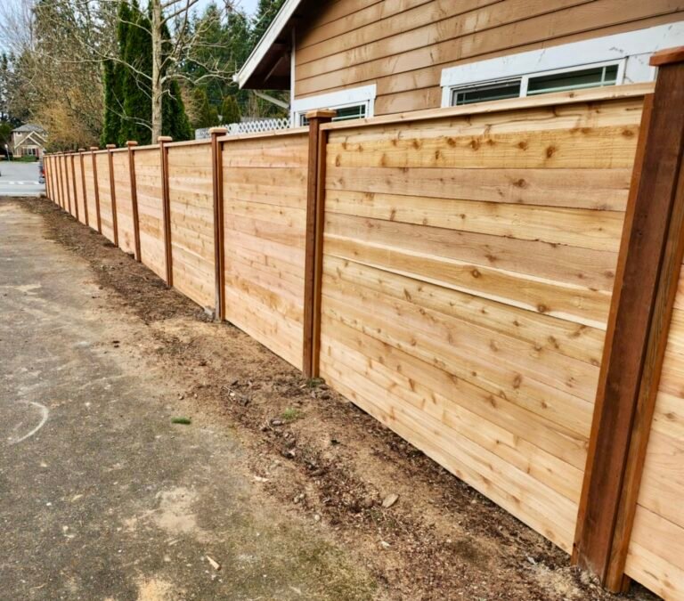 Horizontal cedar privacy fence with capped posts beside a home